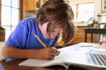 Jeune garçon à la maison écriture et dessin dans son tampon de dessin — Photo de stock