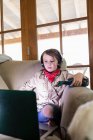 Jeune garçon en tenue safari et écouteurs regardant un film sur ordinateur portable — Photo de stock