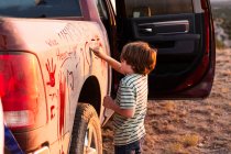 Мальчик пишет на грязном пикапе — стоковое фото