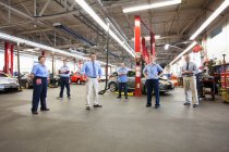 Retrato de seis mecánicos en taller de reparación de automóviles visto desde arriba - foto de stock