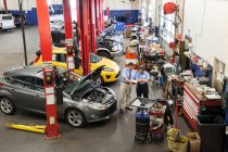 Proprietario di officina di riparazione auto parlando con meccanico femminile ispanico — Foto stock