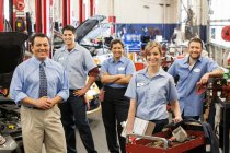 Retrato de sorrindo equipe oficina de reparação de automóveis com proprietário masculino hispânico — Fotografia de Stock