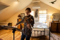 Девочка-подросток играет на скрипке в своей спальне — стоковое фото