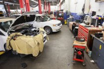 Auto e macchinari in un'officina di riparazione auto. — Foto stock