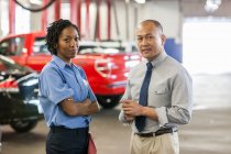 Masculino Pacific Islander gerente de oficina de reparação de automóveis falando com feminino mecânico hispânico — Fotografia de Stock
