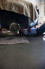 Meccanico che posa su un carrello sotto un'auto in un'officina di riparazione auto — Foto stock
