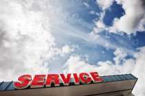 Auto-Service-Schild gegen teilweise wolkenverhangenen blauen Himmel von unten gesehen — Stockfoto