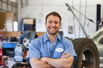 Retrato de un mecánico caucásico sonriente en un taller de reparación de automóviles - foto de stock