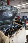 Compartimento de motor abierto de un coche cubierto y listo para un mecánico en taller de reparación de automóviles - foto de stock