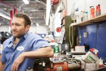 Retrato de um sorridente branco mecânico masculino em uma oficina de reparação de automóveis — Fotografia de Stock