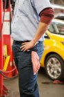 Torso of a mechanic with his hands on his hips in an auto repair shop — Stock Photo