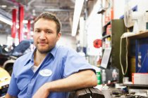 Porträt eines lächelnden kaukasischen Mechanikers in einer Autowerkstatt — Stockfoto
