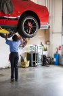 Mechanic in a repair shop working on the underside of a car up on a lift — Stock Photo