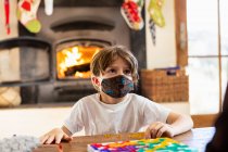 Junge mit Maske spielt Brettspiel zu Hause — Stockfoto