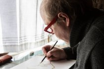 Mature artist at work drawing on paper, a wildlife study of birds. — Stock Photo