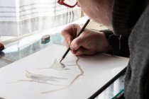 Зрілий художник на роботі малює на папері, дослідження дикої природи птахів . — стокове фото