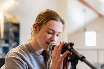 Четырнадцатилетняя девочка-подросток играет на гитаре и поет дома в мансарде — стоковое фото