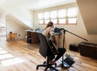 Adolescente de quatorze ans jouant de la guitare et chantant à la maison dans l'espace loft — Photo de stock