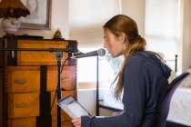 Дівчина-підліток співає в мікрофон у своїй спальні — стокове фото