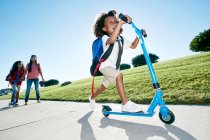 Rapaz de seis anos numa scooter, seguido da irmã — Fotografia de Stock