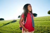 Young mixed race girl in pink shirt and formal tie, wearing a backpack — Stock Photo