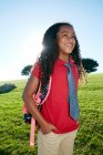 Young mixed race girl in pink shirt and formal tie, wearing a backpack — Stock Photo