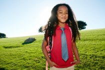 Молода змішана дівчина гонки в рожевій сорочці та офіційній краватці, в рюкзаку — стокове фото