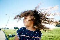 Young mixed race girl having fun outdoors, curly hair fanning out — Stock Photo