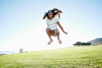 Jeune fille de race mixte avec de longs cheveux bouclés bondissant dans l'air — Photo de stock