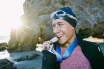 Giovane donna, triatleta in giacca mordere una grande medaglia con i denti, un vincitore — Foto stock