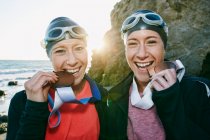 Zwei Schwestern, Triathleten, die in Badebekleidung, Schwimmmützen und Schwimmbrillen ihre großen Medaillen tragen, Sieger. — Stockfoto