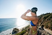 Young woman, triathlete in training in swimwear, swim hat and goggles on a beach. — Stock Photo