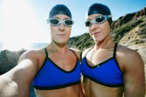 Дві сестри, триатлоністи тренуються в купальнику, плавають капелюхами та окулярах . — стокове фото