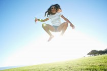 Giovane ragazza di razza mista con lunghi capelli ricci che saltano in aria — Foto stock