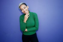 Young black woman smiling and looking aside on blue background — Stock Photo