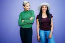 Zwei junge Frauen stehen nebeneinander vor schlichtem Hintergrund — Stockfoto