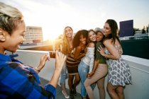 Группа молодых женщин тусуется на городской крыше в сумерках — стоковое фото