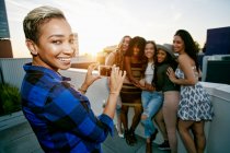 Gruppo di giovani donne che festeggiano sul tetto di una città al tramonto — Foto stock