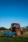 Tractor rojo con grada azul en una granja. - foto de stock