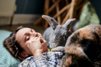 Mulher deitada no chão alimentando dois coelhos da casa de estimação — Fotografia de Stock