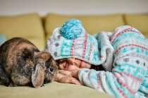 Donna sdraiata con gli occhi chiusi accanto al coniglio domestico marrone — Foto stock