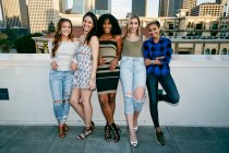 Fünf junge Frauen posieren für Fotos auf einem Dach, Hintergrund der Skyline der Stadt — Stockfoto