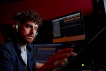 Чоловік працює в музичній студії, використовуючи комп'ютерні навушники — стокове фото