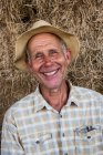 Portrait of smiling man wearing checkered shirt and sun hat, looking at camera. — Foto stock