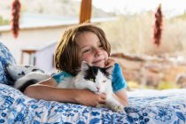 Junge liegt auf Außenbett und umarmt Katze — Stockfoto