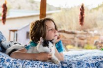 Мальчик лежит на открытой кровати обнимая кота — стоковое фото