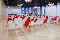 Large empty room with red and white chairs in rows, ready for a presentation — Photo de stock