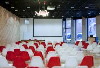 Large empty room with red and white chairs in rows, ready for a presentation — Photo de stock
