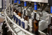 Завод по розливу пива с движущимися лентами, рядами бутылок, автоматизированным процессом, укупоркой и маркировкой и размещением в ящиках — стоковое фото