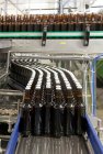 Beer bottling plant with moving belts, rows of bottles, automated process, capping and labelling and placing in crates — Stock Photo